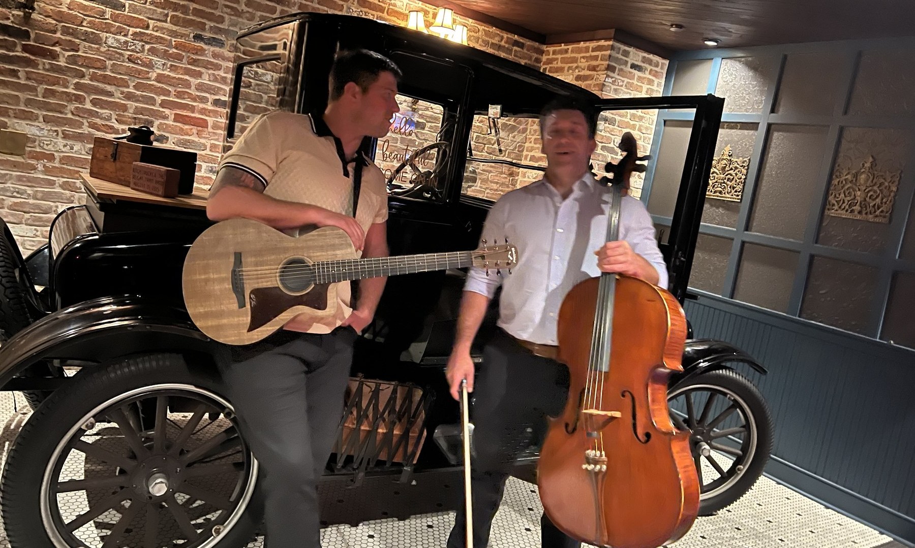 Guitar and cello duo in front of vintage car