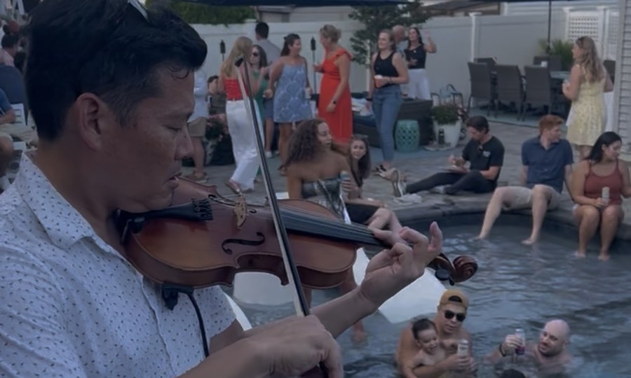 Violinist performing poolside at a private party with guests